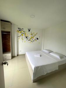 1 dormitorio con 1 cama con pájaros en la pared en APARTA HOTEL Y TERRAZA SAMANES en Florida