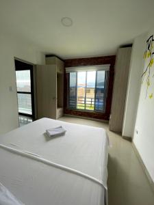 Cama blanca en habitación con ventanas grandes en APARTA HOTEL Y TERRAZA SAMANES en Florida