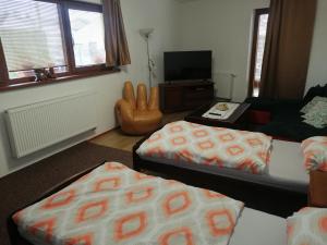 una sala de estar con 2 camas y una silla en Útulný Domček Privat Bedrich en Poprad