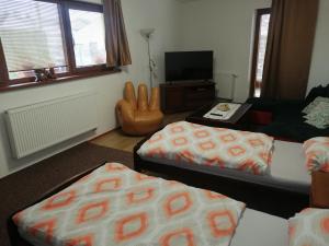 salon z 2 łóżkami i krzesłem w obiekcie Útulný Domček Privat Bedrich w Popradzie
