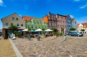 um grupo de edifícios e uma rua com mesas e cadeiras em AnaCapri Gästehaus Lugano em Ueckermünde