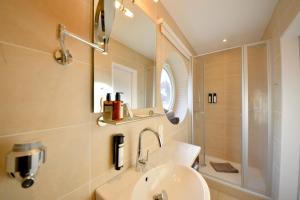 a bathroom with a sink and a shower and a mirror at Haus Poseidon - Wohnung 1 1 in Wangerooge
