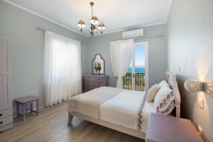 a white bedroom with a bed and a window at Villa Levanda (Loggos Paxos) in Longós