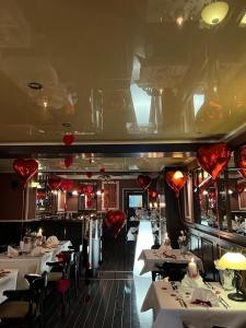 un restaurante con mesas blancas y corazones rojos en el techo en AnaCapri Gästehaus Lugano, en Ueckermünde