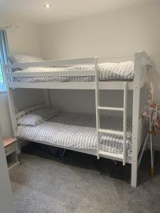 2 białe łóżka piętrowe w pokoju w obiekcie Lovely 3 Bed Bungalow with garage, close to Brecon Beacons & Bike Park Wales w mieście Merthyr Tydfil