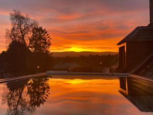 a sunset over a swimming pool at sunset at Garden Park Guest House in Grantown on Spey