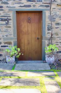 een houten deur op een stenen gebouw met twee potplanten bij Stables by the Vines in Mintaro