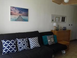 czarna kanapa z poduszkami w salonie w obiekcie Beau studio vue mer Canet Sud w mieście Canet-en-Roussillon