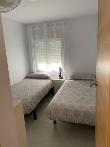 1 dormitorio con 2 camas y ventana en Ático en Barbate, en Barbate