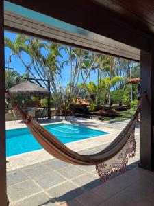 a hammock on a patio next to a swimming pool at Casa 10 suítes, até 64 pessoas, Praia Ferradura in Búzios