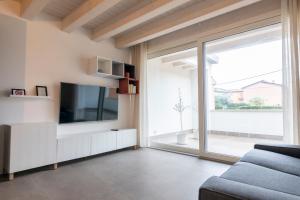 Una sala de estar con televisión y una gran ventana. en Verona Urban Apartment, en Verona