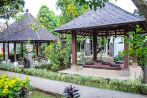 a pavilion with a bench in a garden at Araminth Guest House and Spa in Lovina
