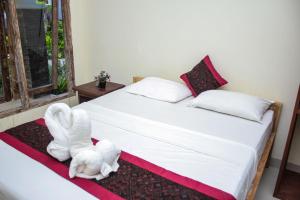 a bedroom with a bed with a towel animal on it at Araminth Guest House and Spa in Lovina