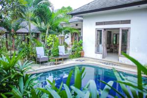 a villa with a swimming pool and a house at Araminth Guest House and Spa in Lovina