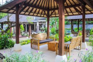 a wooden bench under a gazebo in a garden at Araminth Guest House and Spa in Lovina