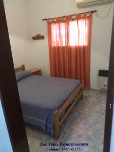 1 dormitorio con cama y cortina de color naranja en Los Tales Departamentos en Colón