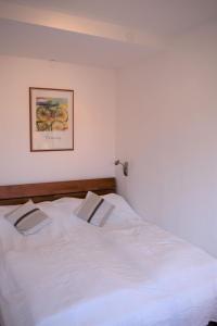 a white bed in a bedroom with a picture on the wall at Haus-am-Deich-Wohnung-10 in Dahme