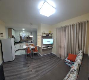 a living room with a couch and a table and a kitchen at Apartamento espaçoso e impecável in Bento Gonçalves