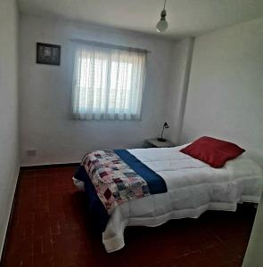 1 dormitorio con cama con almohada roja y ventana en Blue Wind en Comodoro Rivadavia
