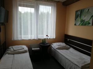 2 Betten in einem Zimmer mit Fenster in der Unterkunft Gościniec Biznesowy in Dąbrowa Górnicza