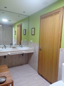 baño con 2 lavabos y puerta de madera en Apartamento Isidro Parga Pondal, en Laxe