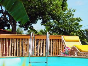 uma piscina com duas cadeiras e uma cerca de madeira em S'cale TropiKal - Gite cosy avec piscine privée em Petit-Canal