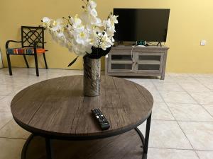 a vase of flowers on a table with a remote control at St Bess Comfort Style in Black River