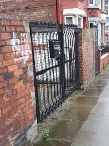 een zwarte poort aan de zijkant van een stenen muur bij Litherland Apartment in Litherland