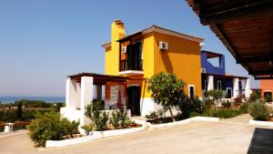 a yellow and white house with plants in front of it at Ilis Villas in Kyllini