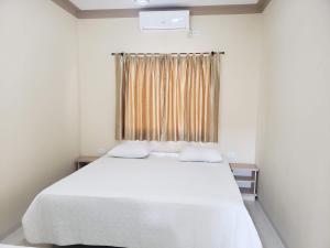 a bedroom with a white bed and a window at Felipe Family Houses - Casas de temporada in Foz do Iguaçu