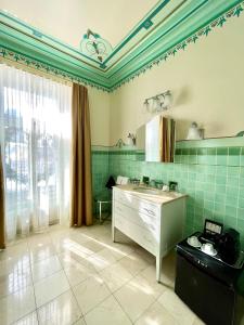 uma cozinha com azulejos verdes, um lavatório e uma janela em Hotel Manoir D'Auteuil em Quebeque