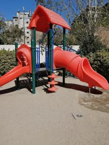 een speeltuin met een rode glijbaan in een park bij Nuevo Amanecer in Santiago