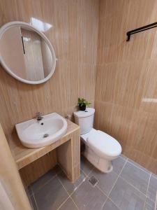 un bagno con un water, un lavandino e uno specchio di Sand 1 Hostel a Siquijor