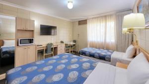 a hotel room with two beds and a desk at Cootamundra Gardens Motel in Cootamundra