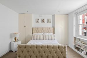 a bedroom with a large bed with a tufted headboard at Kensington two floor mews house in London