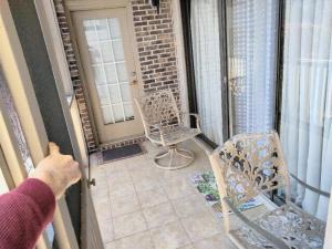 a person opening the door to a balcony with a chair at Unique 2 Bedroom / 2 Bath Condo in Myrtle Beach in Myrtle Beach