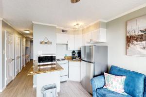 a kitchen with white cabinets and a blue couch at Sun of a Beach in Galveston