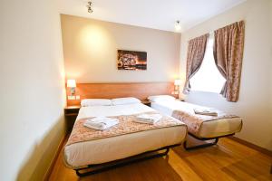 a hotel room with two beds and a window at Kings Cross Inn Hotel in London