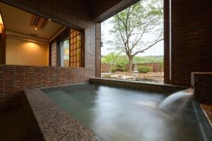 a swimming pool in a brick house with a waterfall at Onogawa Onsen Kajikaso in Yonezawa