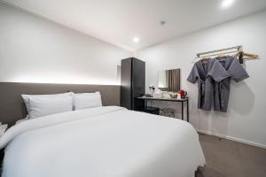 a bedroom with a large white bed and a sink at Jawoori Hotel Incheon Songdo in Incheon