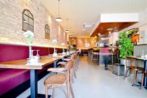 a restaurant with wooden tables and chairs and a brick wall at Kings Cross Inn Hotel in London