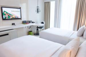 a hotel room with two beds and a flat screen tv at The Stones Hotel - Legian Bali, Autograph Collection in Kuta