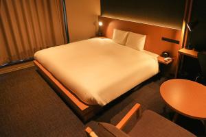 a hotel room with a large bed and a table at N Plus Hotel Akihabara in Tokyo