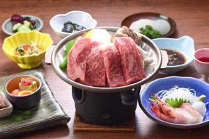 a table with a bowl of meat and bowls of food at Ryokan Tamura in Kusatsu