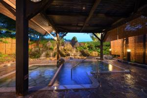 a swimming pool in a house with a waterfall at Onogawa Onsen Kajikaso in Yonezawa