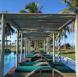 uma fila de espreguiçadeiras verdes ao lado de uma piscina em Villa Oberoi pé na areia alto luxo em Santo André