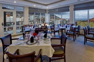 uma sala de jantar com mesas, cadeiras e janelas em Hotel Orquidea em Funchal
