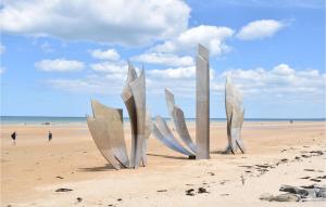 a sculpture on a beach with the ocean in the background at Pet Friendly Stacaravan in Grandcamp-Maisy