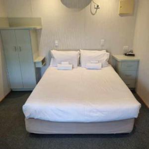 a bedroom with a large white bed with two pillows at Alexandra Parklife Deluxe Studio 2 in Alexandra