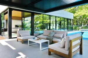 a living room with glass walls and a pool at Bridle Path Retreat - Christchurch Holiday Homes in Christchurch